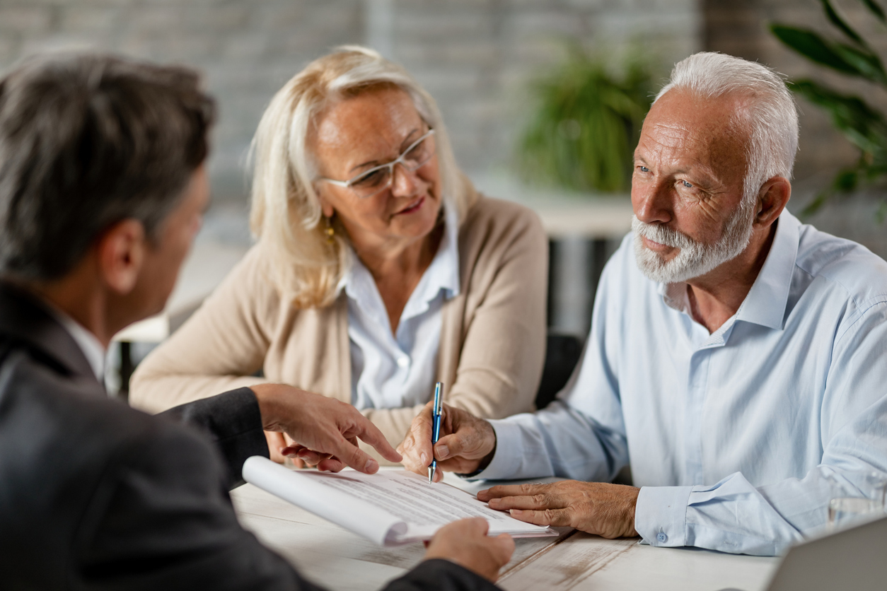 Senior couple signing a contract while having a meeting with insurance agent in the office.